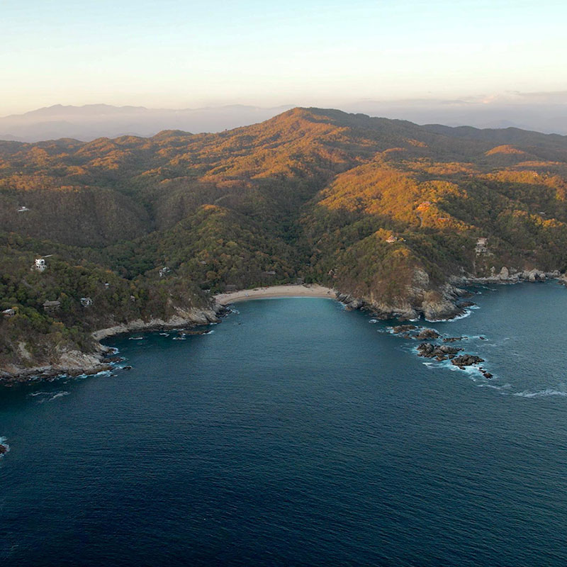 Aerial view of beachfront land for sale on Playa La Boquilla on the Pacific coast of Oaxaca Mexico surrounded by forested hills